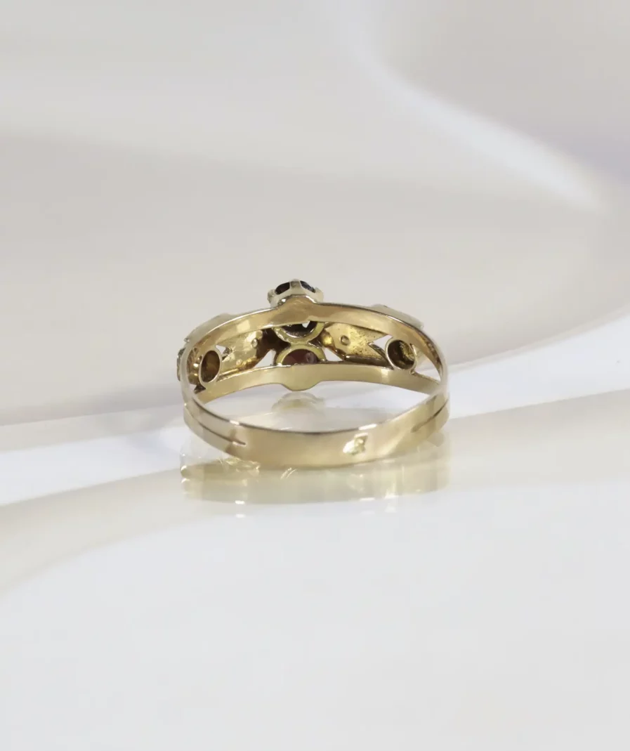 Bague ancienne de dos en or rose. La bague est posée sur un fond neutre beige